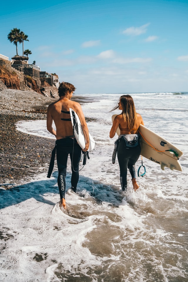 Surfing couple enjoying off-the-beaten-path honeymoon destinations